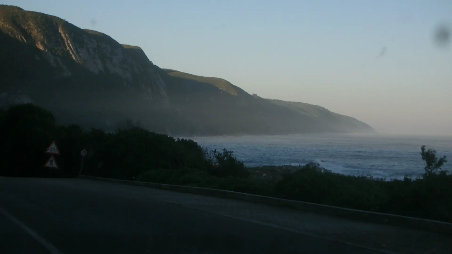 An open coastal road at first light, with the ocean beside it